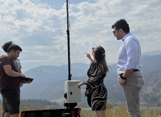The Bayes Studio team stands on a hillside in Interior British Columbia, demonstrating their stationary multimodal monitoring unit.